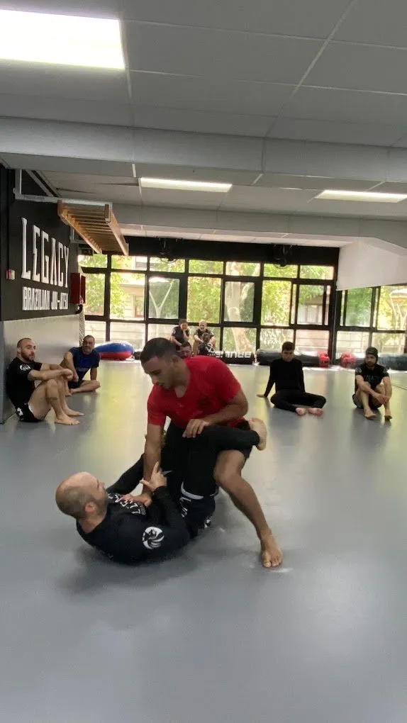 Clase de BJJ con alumnos alrededor del tatami